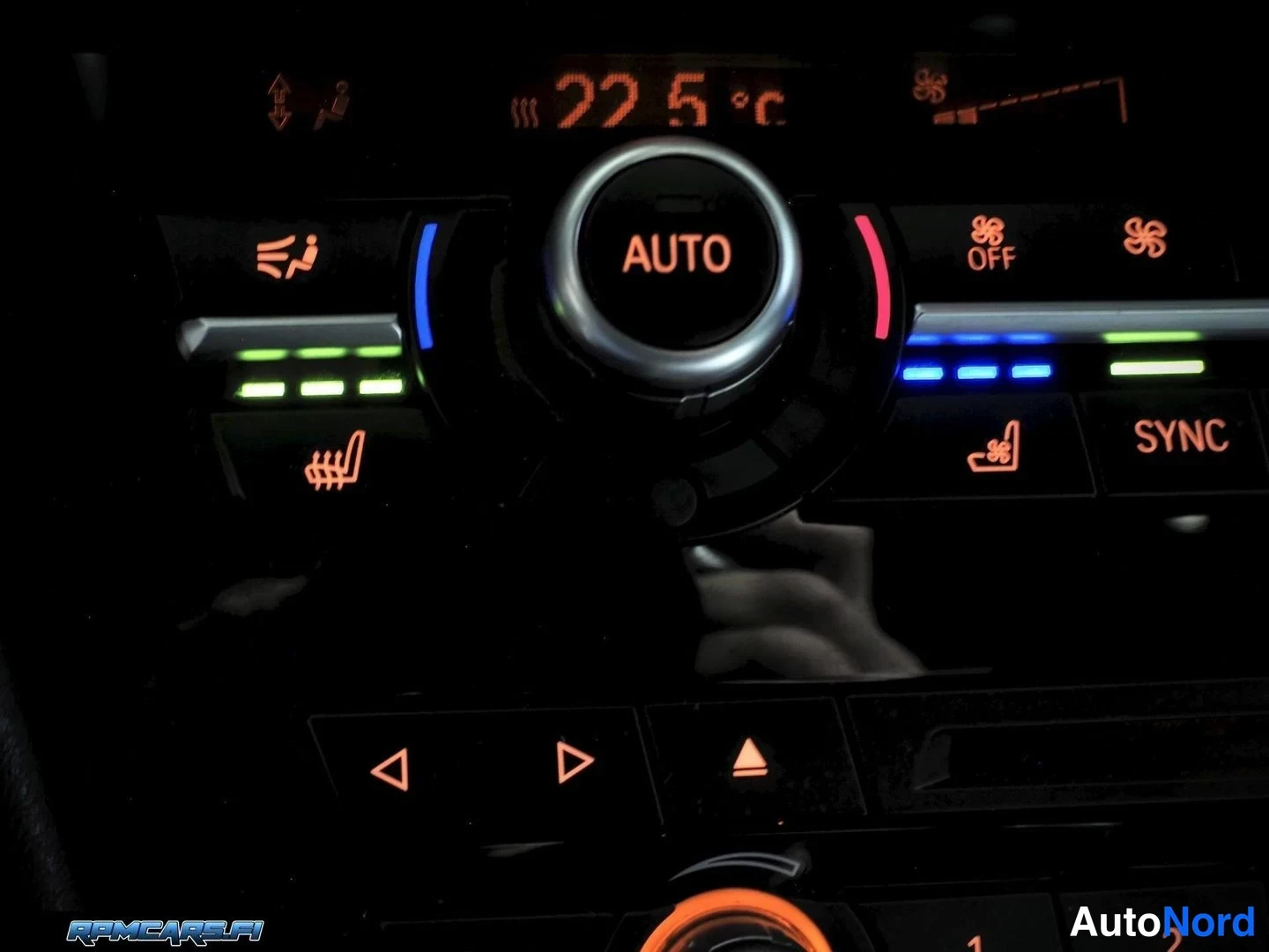 Yksityiskohta: Lähi Kuva BMW:n ilmastointipaneelista: AUTO-näppäin keskellä, näytössä 22,5 °C, SYNC-näppäin sekä lämmitys- ja tuuletusmerkit valaistuina.