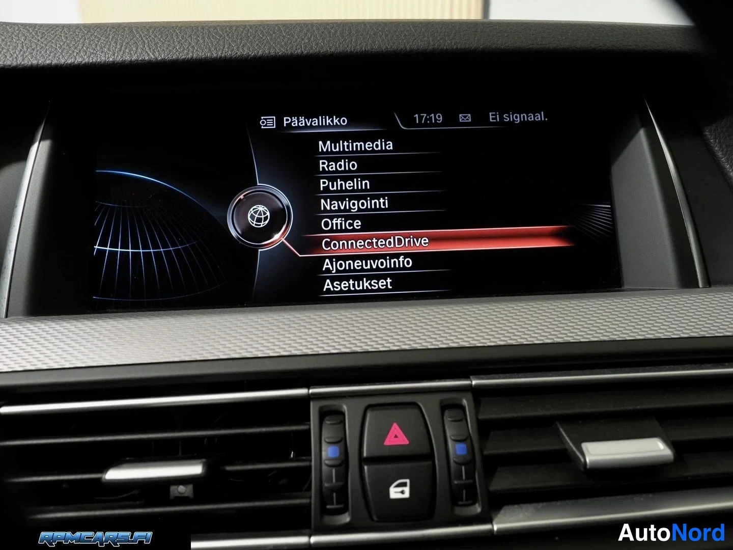 Muu: Lähikuva auton infotainment-näytöstä, jossa on valikko Päämääritys: Multimedia, Radio, Puhelin, Navigointi, Office, ConnectedDrive, Ajoneuvoinfo ja Asetukset.