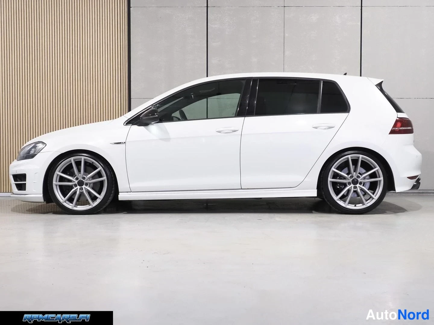 Sivulta: Valkoinen Volkswagen Golf sivusta kuvattuna, hopeiset kevytmetallivanteet ja tummat ikkunat.