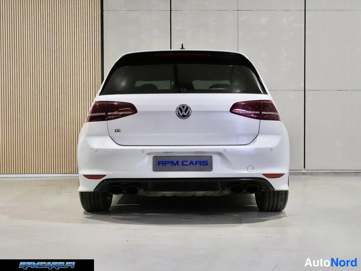 Takaa: Auton takaosa suoraan takaa: valkoinen korimalli, punaiset takavalot, VW-merkki ja neljä pakoputkea. Rekisterikilven paikalla lukee APM CARS.