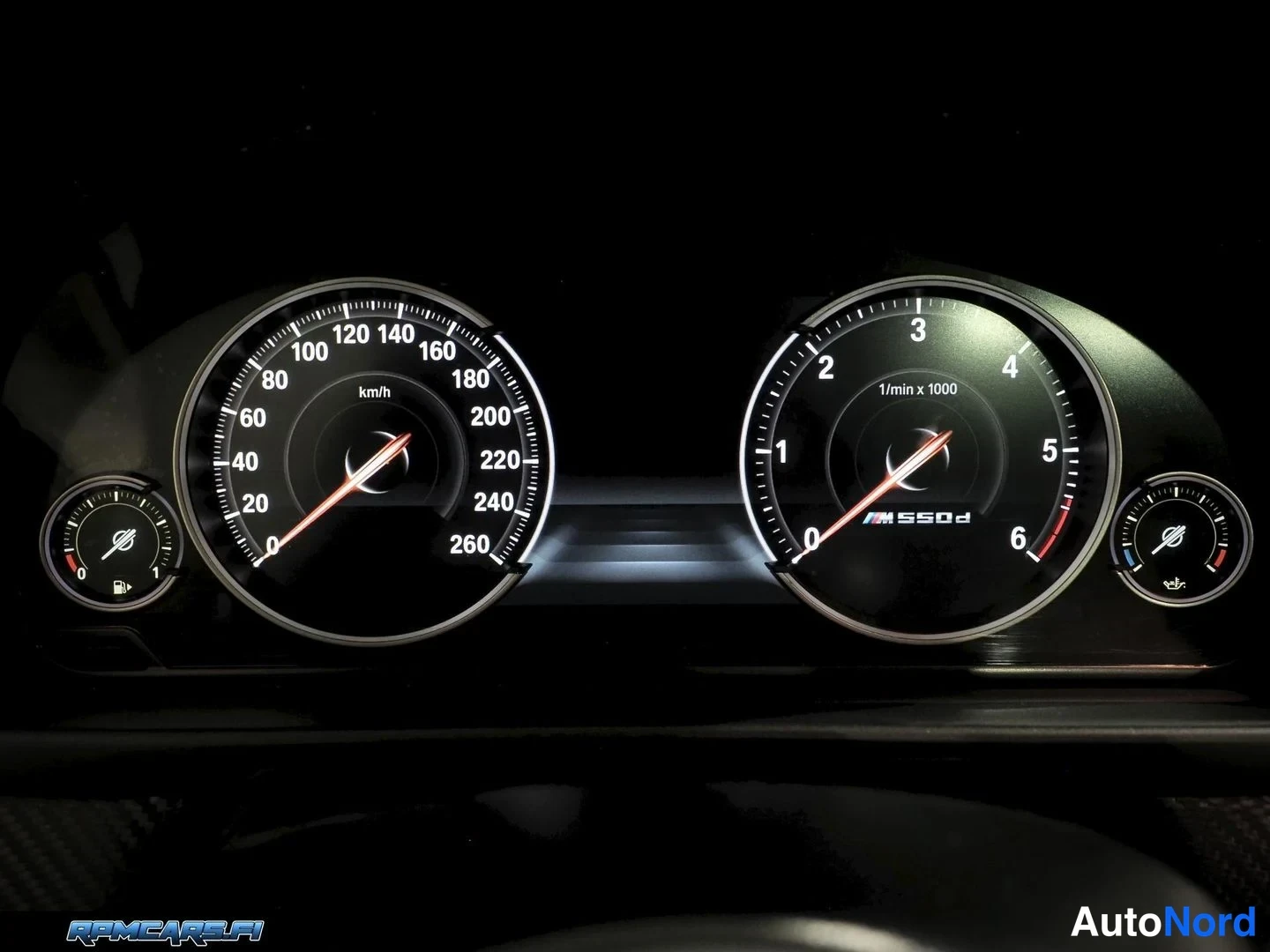 Muu: BMW M550d -mittaristo pimeässä: nopeusmittari 260 km/h asti ja kierrosmittari 1/min x 1000, M550d-merkintä näkyvissä.