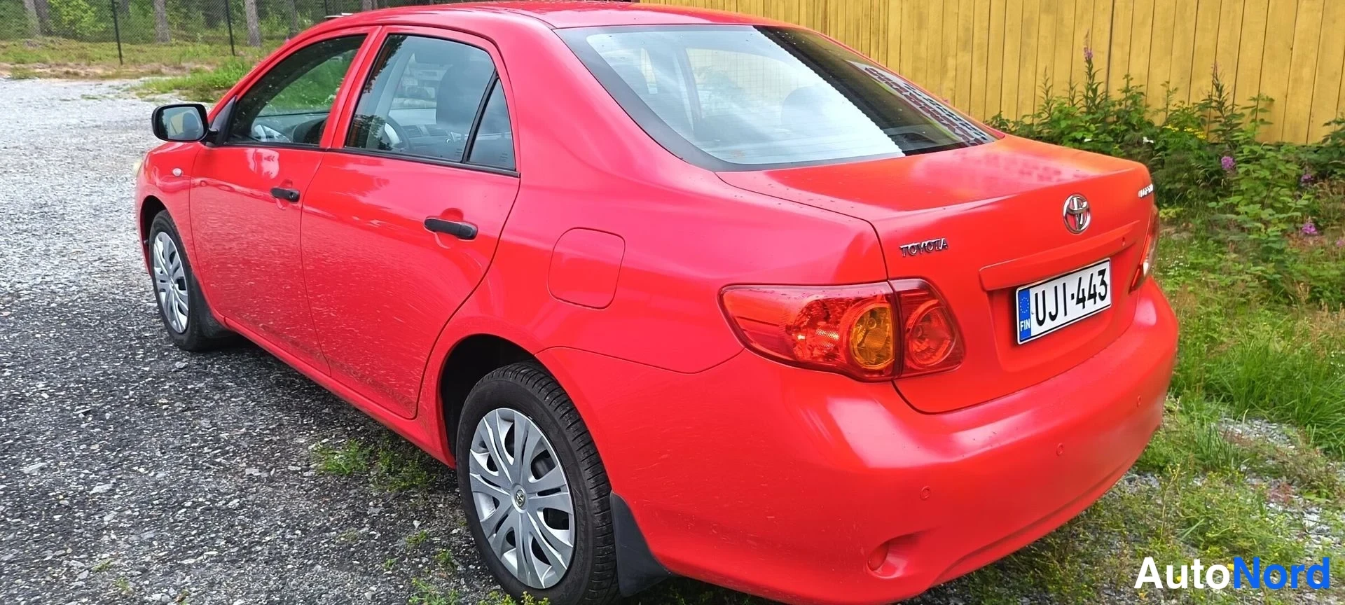 Takaviisto: Punaisen sedanin takakolmasosa, rekisteritunnus, Toyota-koriste takaluukissa.