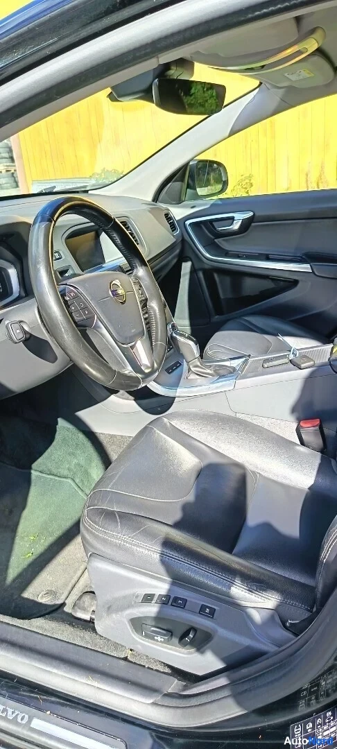 Yksityiskohta: Ohjaamo etupenkillä: Volvo-ohjauspyörä, vaihtajan kahva ja musta nahkaistuin.
