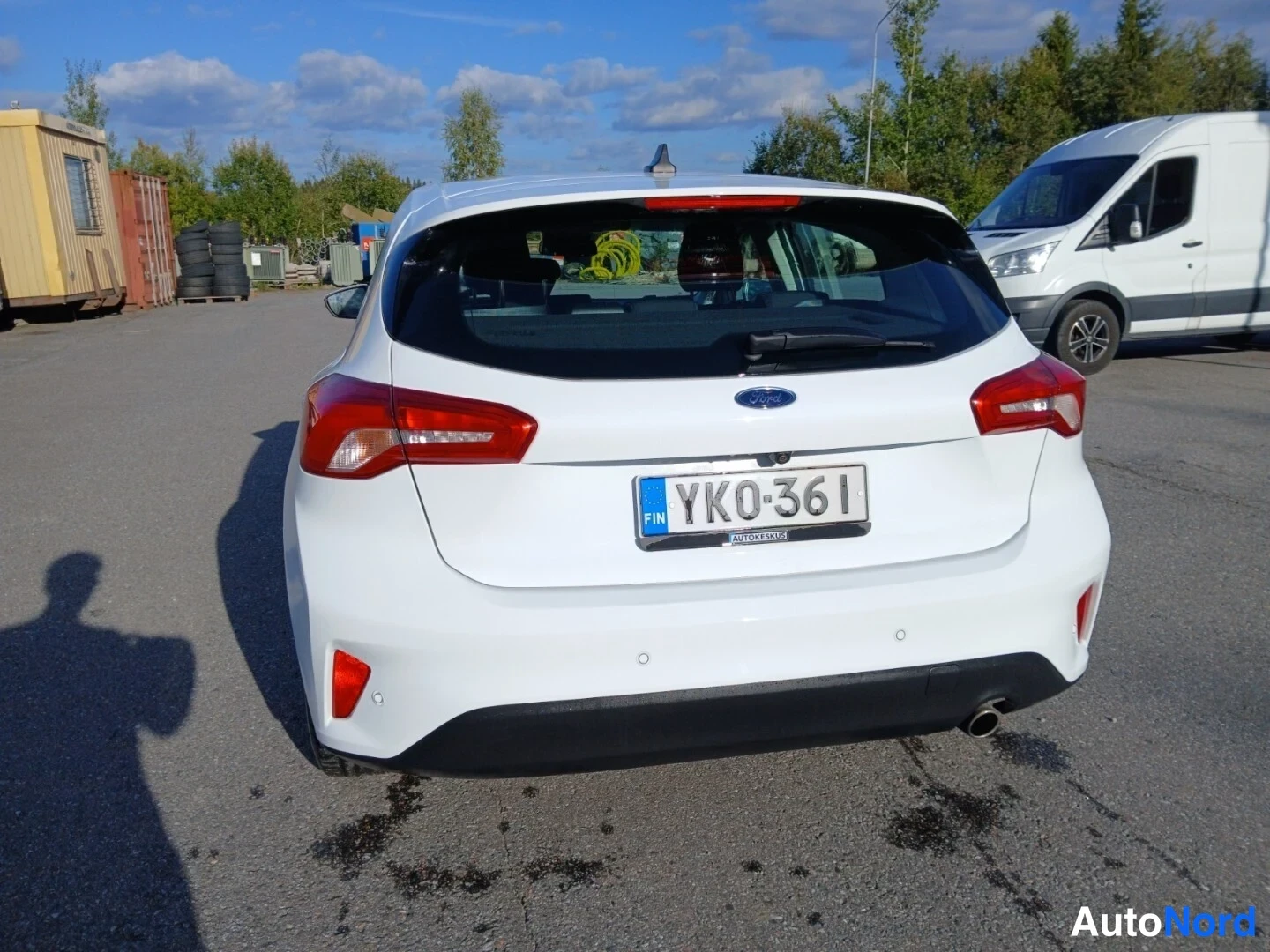 Takaa: Valkoisen Ford Focus -viistoperän takapuoli, takavalojen ja YK0-361-rekisterikilven näkyvissä.