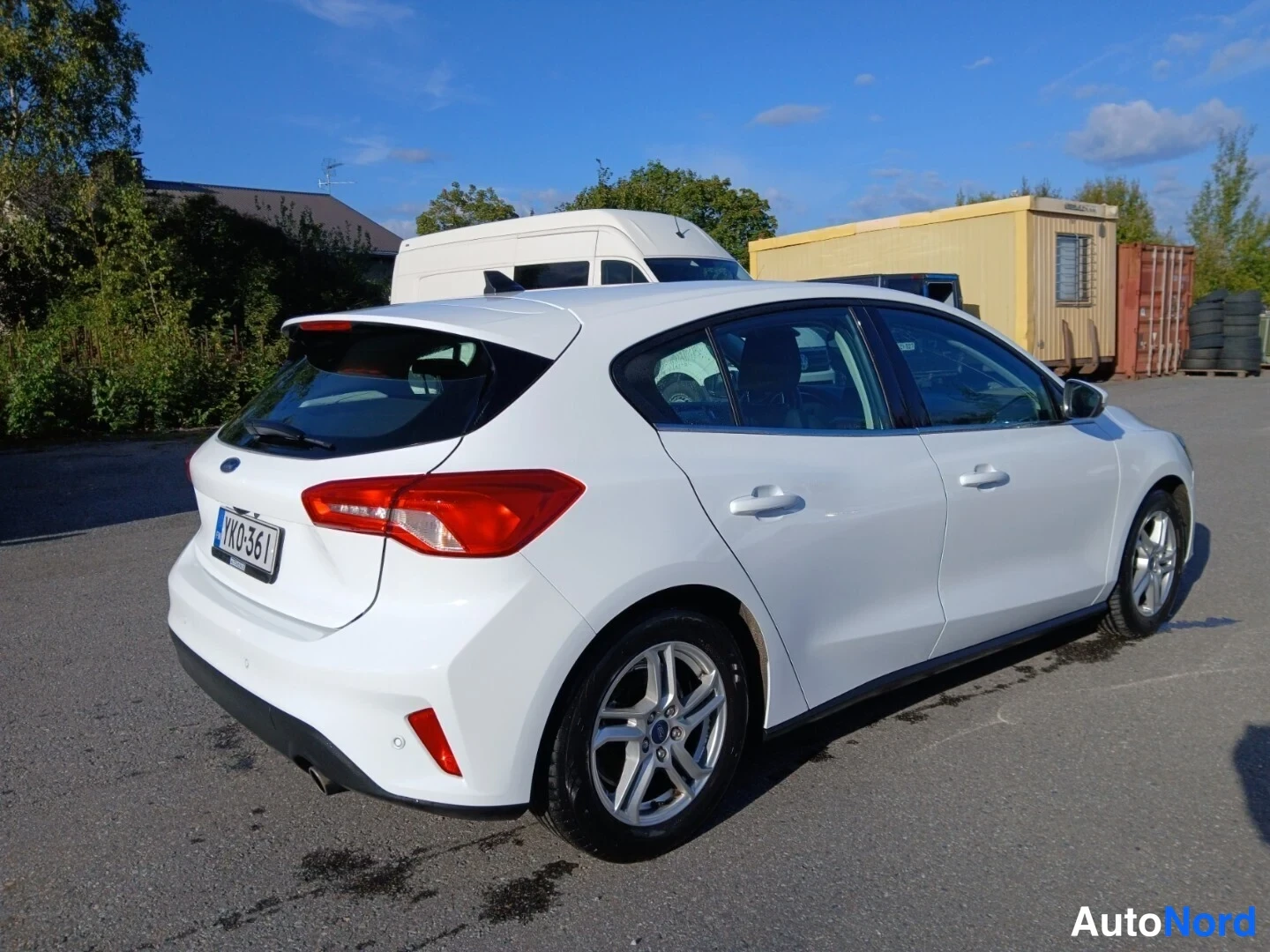 Takaviisto: Valkoinen Ford Focus viistoperä sivulta-takaa kuvattuna, vasen sivu ja takamootti näkyvissä.
