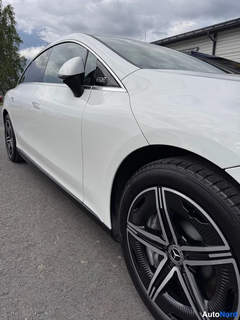 Sivulta: Mercedes-Benz EQE:n etummainen ovenpinta ja musta moniosa-vanne tummanpuhuvaan urbaaniin ympäristöön.
