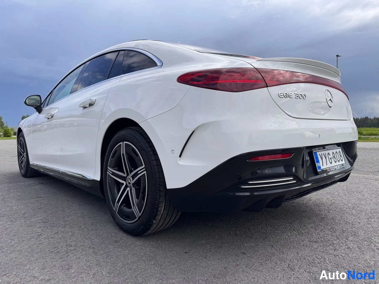 Takaviisto: Valkoinen Mercedes-Benz EQE 300 sedan takakulma oikealta lähikuvassa,Punaiset poikittain asennetut takavalot, musta basattikolmiot, rekisterikilpi.