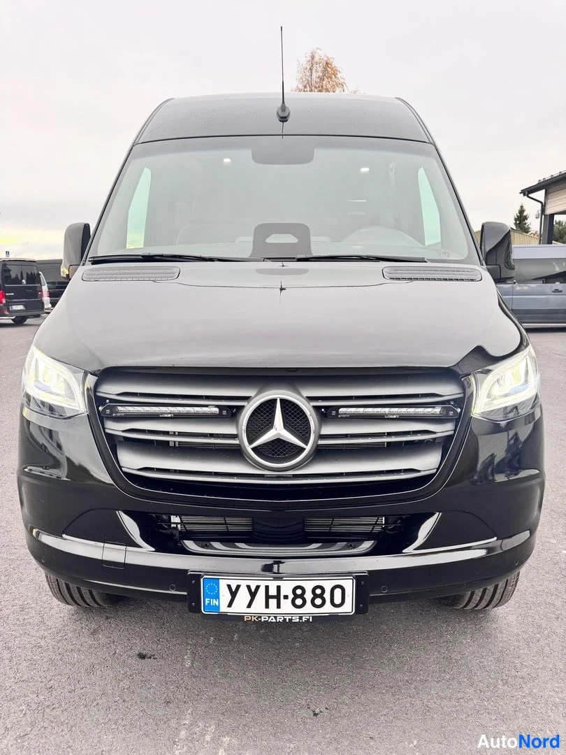 Edestä: Musta Mercedes-Benz Sprinter -pakettiauto etupuolelta suoraan kuvattuna; etusäleikössä Mercedes-tähti, rekisteritunnus.