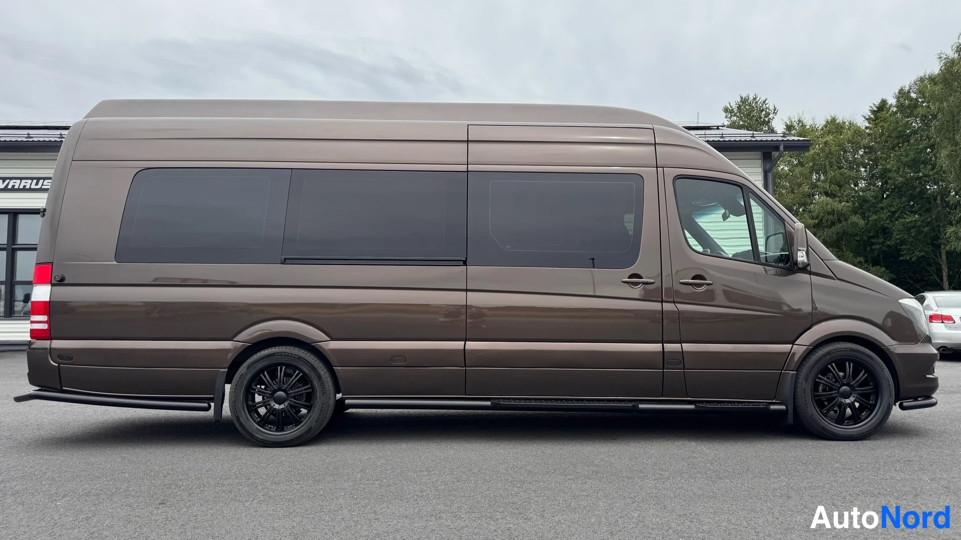 Sivulta: Ruskea Mercedes-Benz Sprinter -pakettiauto sivulta, tummat ikkunat ja mustat kevytmetallivanteet.