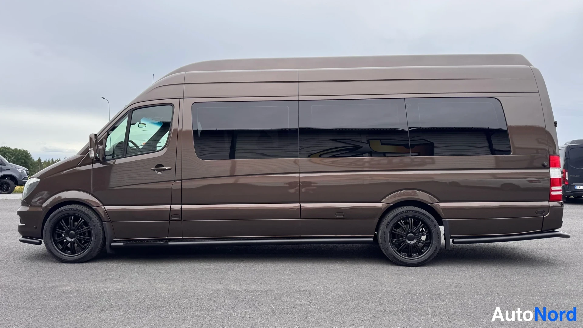 Sivulta: Mercedes-Benz Sprinter -pakettiauton sivukuva vasemmalta, tummanruskea koripinta, tummat ikkunat, mustat kevytmetallivanteet.