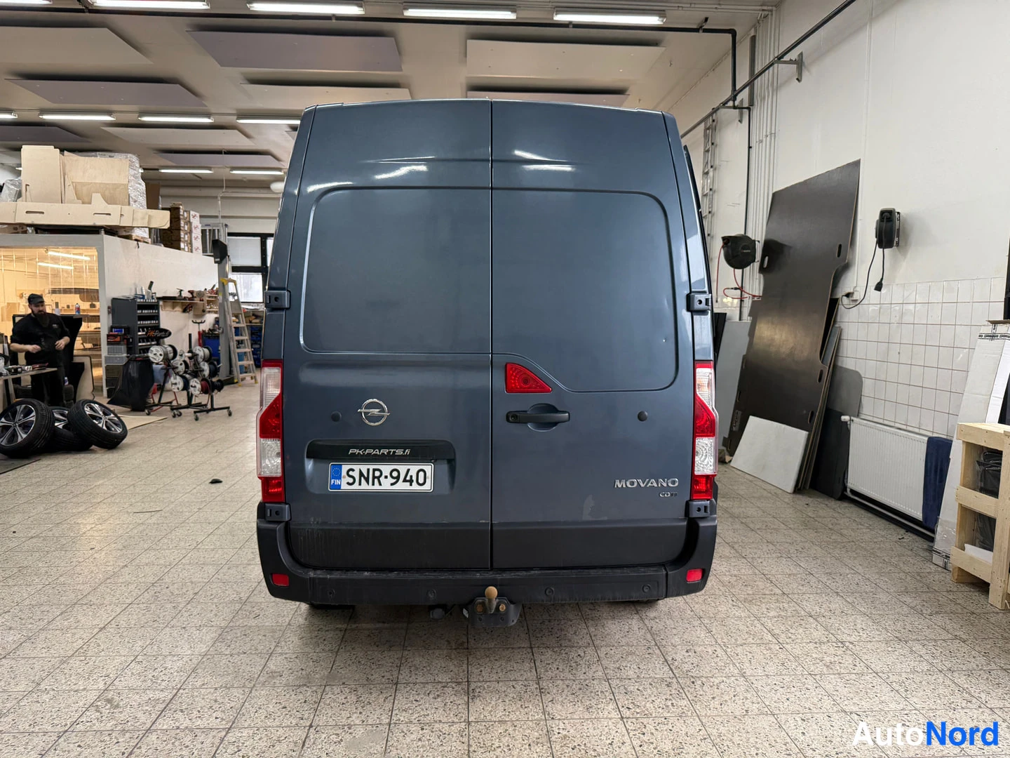 Takaa: Opel Movano -pakettiauton perä suoraan takaa, rekisterikilpi, MOVANO-teksti ja Opel-merkki näkyvissä.