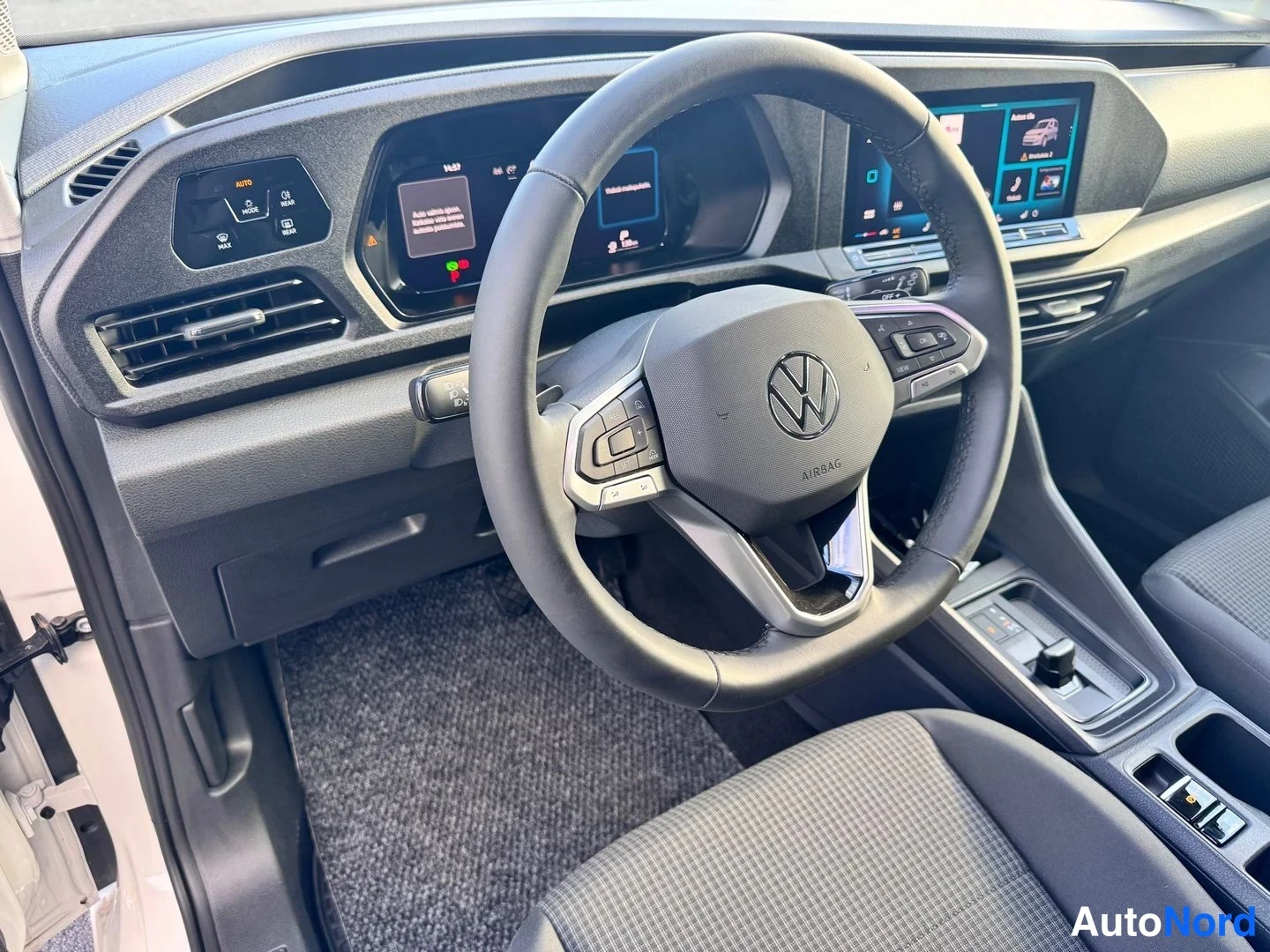 Muu: Ohjauspyörän lähikuva: Volkswagen-merkki ja Airbag-teksti, vasemmalla mittaristonäyttö ja oikealla infotainment-näyttö.