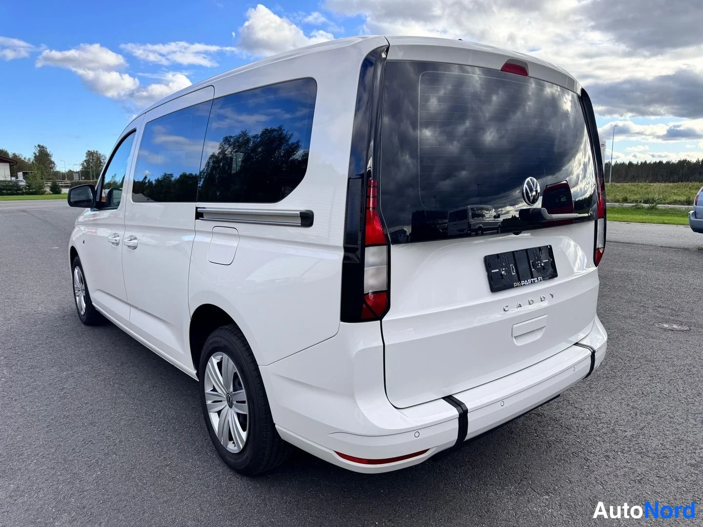 Takaviisto: Valkoisen Volkswagen Caddy -pakettiauton takaosa ja oikea kylki takakulmasta kuvattuna paikoitusalueella.