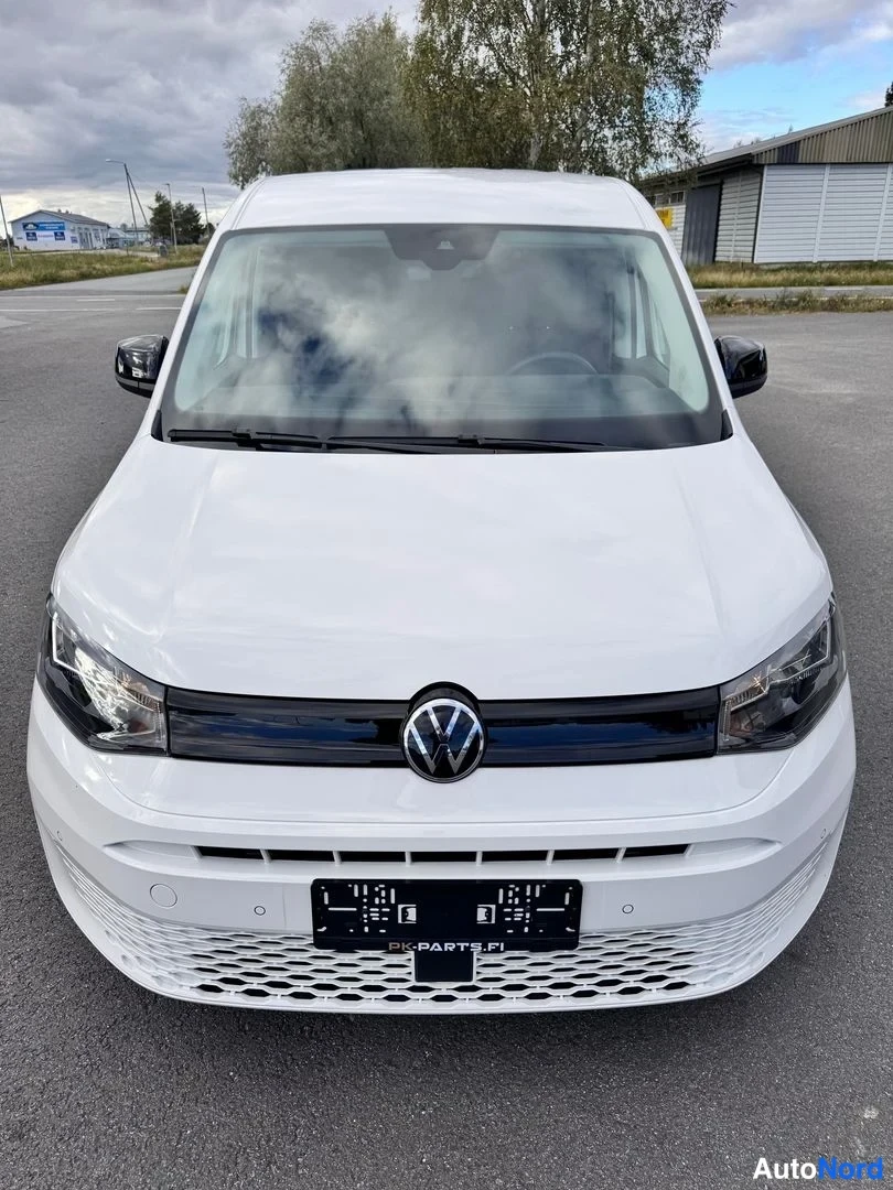 Edestä: Volkswagen Caddy suoraan edestä kuvattuna, valkoinen kori, keskellä VW-logo ja musta etusäleikkö.