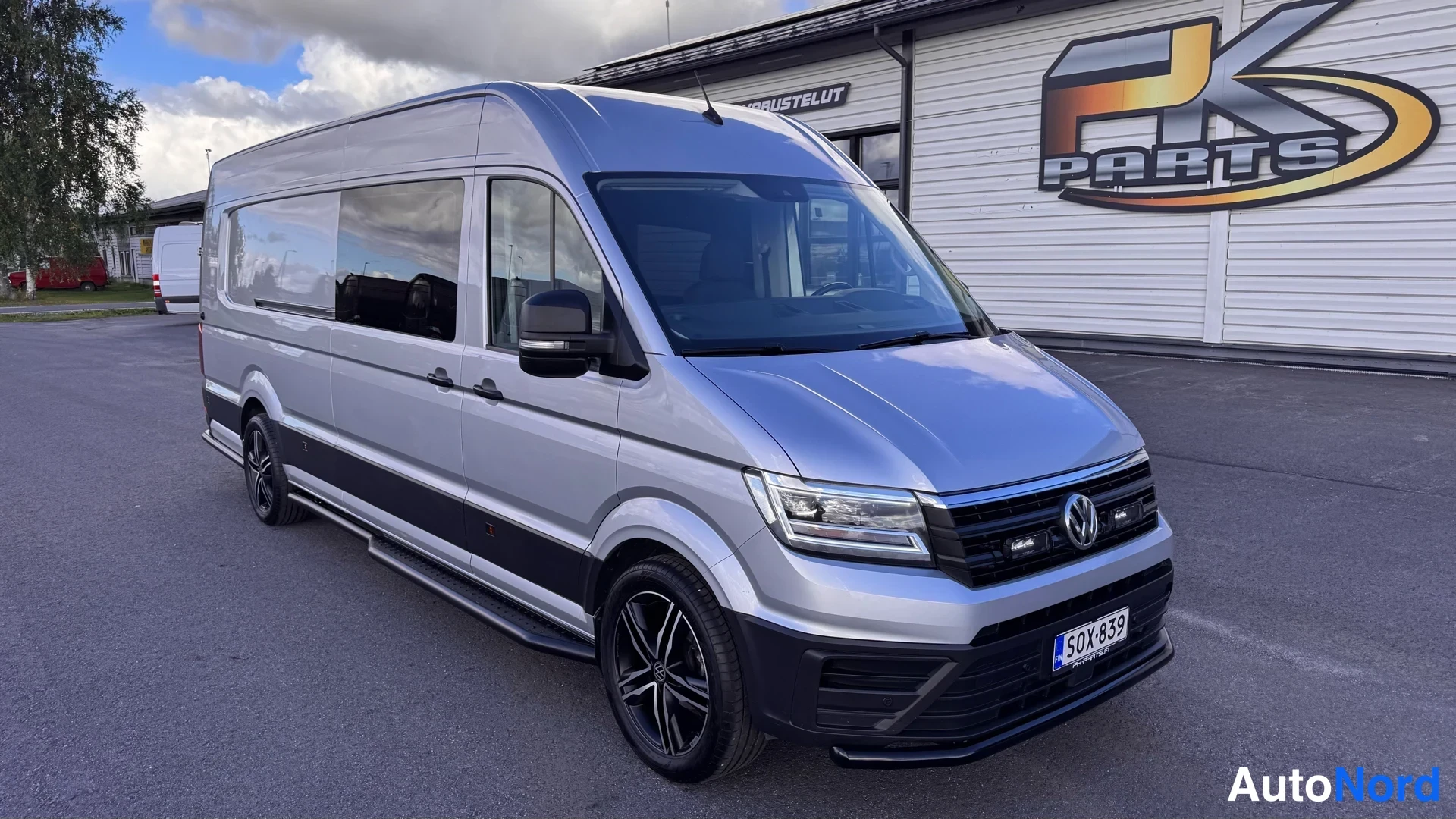 Etuviisto, nokka oikealle: Hopeinen Volkswagen Crafter -pakettiauto etukulmasta, keula ja vasen sivu näkyvät.