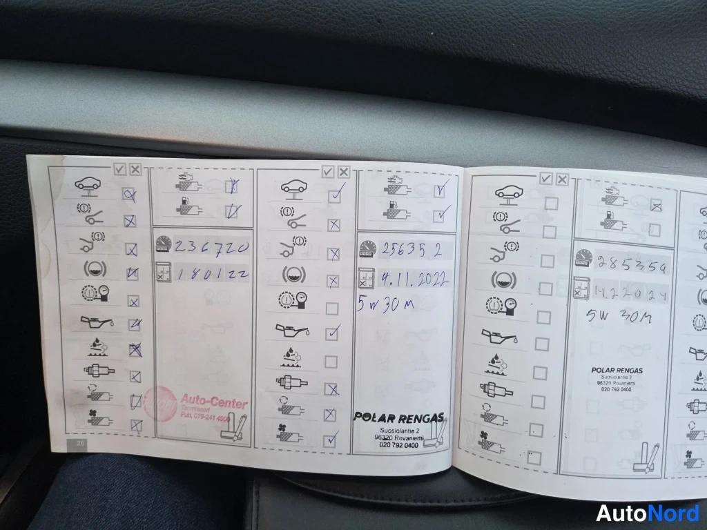 Asiakirja: Auki avattu huoltokirja penkissä, jossa leimoja Auto-Center ja Polar Rengas sekä käsin merkityt lukemat 236720, 180122, 256352, 4.11.2022, 5W30M, 285354, 11.7.2