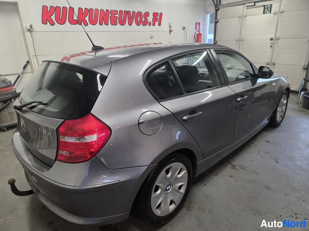 Takaviisto: BMW 1-sarjan takanäkymä viistosti, 116d-takamerkinnän omaava harmaa viistoperä ja vetokoukku näkyvät.