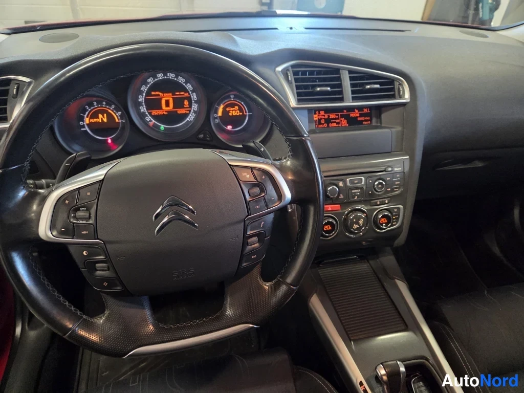 Edestä: Ohjaamo lähikuvassa: Citroenin ohjauspyörä, mittaristo ja keskikonsoli, vaihteenvalitsa ja kaksi lämpötilanäyttöä.