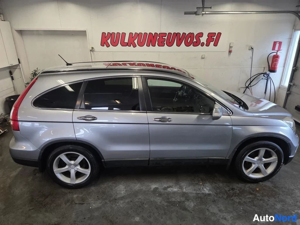 Sivulta: Hyundai? – ei, auton kylki sivulta: hopeanvärinen CR-V tila-autotalli, tummat ikkunat ja viisipaikkainen korirakenne näkyvät