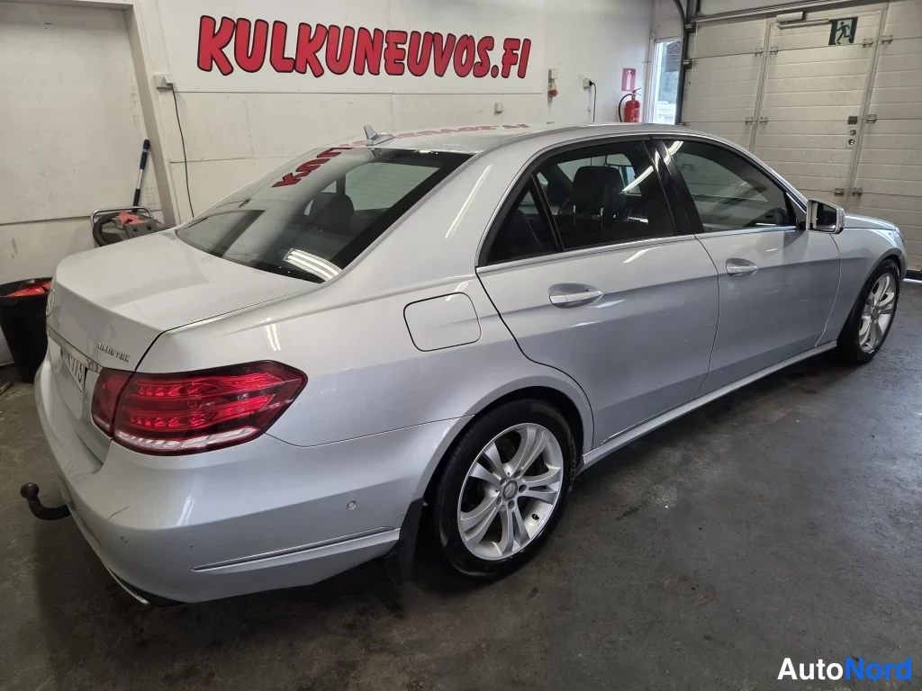 Takaviisto: Mercedes-Benz E-sarjan sedan takaviistosta oikealta, hopeisena hallissa.