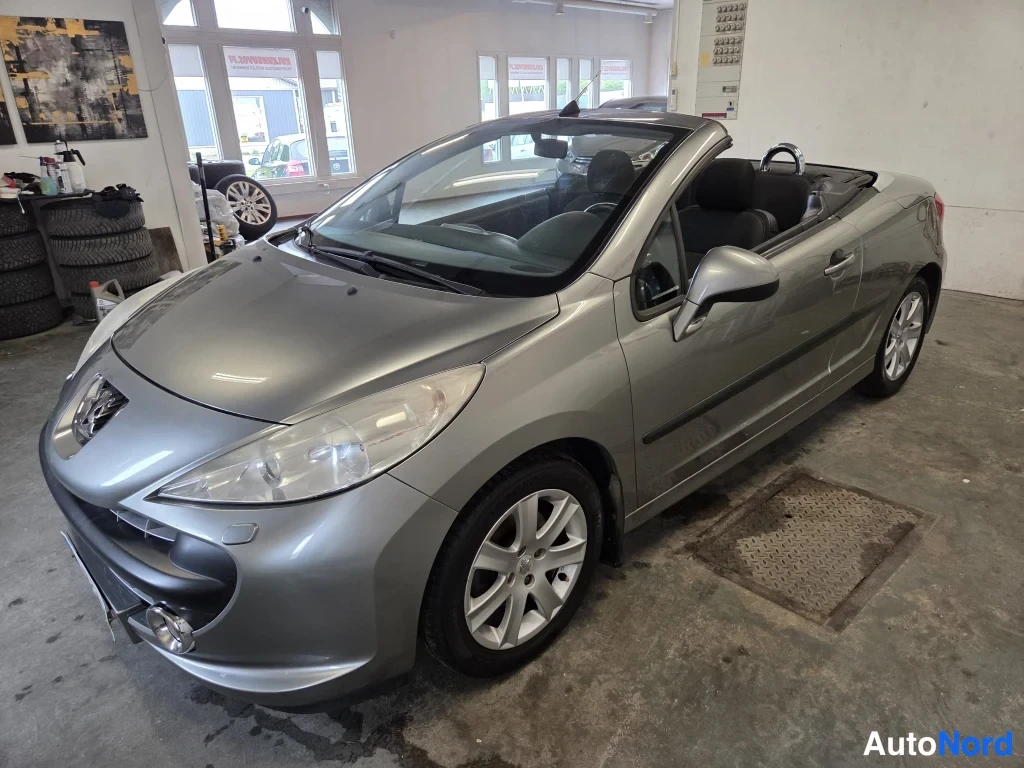 Etuviisto, nokka vasemmalle: Peugeot 207 -avolava hyvin hoidetussa autotallissa, katto auki ja etupää vasemmalle kääntyneenä