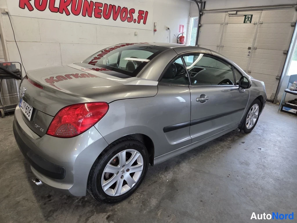 Takaviisto: Peugeot 207:n takaosa ja vasen sivu kolmannesnäkymässä katettuna katto ylhäällä, hopeaharmaa koriväri, rekisterikilpi.