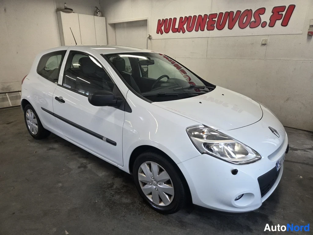 Etuviisto, nokka oikealle: Valkoinen kolmiovinen Renault Clio -henkilöauto kuvattu kolmivartalo-otteesta edestä oikealta hallissa.
