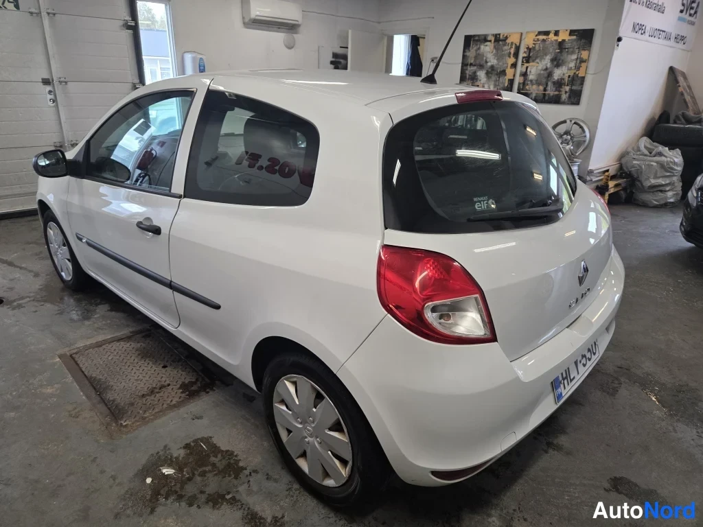 Takaviisto: Valkoinen Renault Clio -henkilöauto takavartalo-otteesta vasemmalta hallissa.