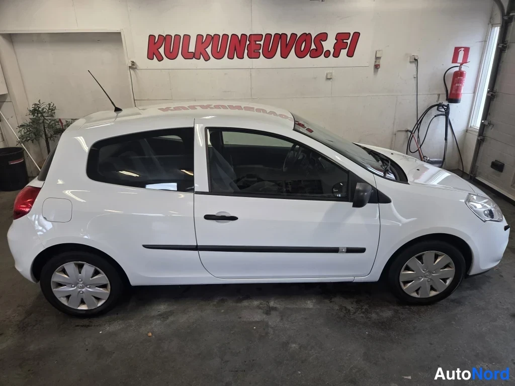 Etuviisto, nokka oikealle: Valkoinen kolmiovinen Renault Clio kuvattu kolmimittelystä edestä oikealle suunnattuna; kylkoviiva, rattaiden suojusteet ja etuvalo näkyvät.