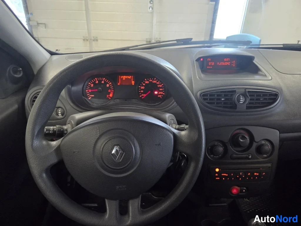 Muu: Renault-merkkiohjaamon sisäkuvanäköala: ohjauspyörä, mittaristo ja kojelauta; matkamittari näyttää 143 942 km.