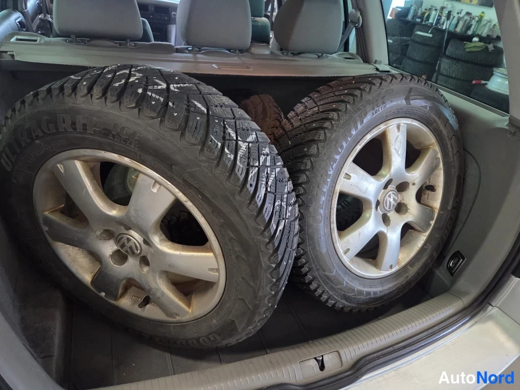 Muu: Auton tavaratilassa on kaksi kohotettuna olevaa tertta pölyä puhdistettua talvirengasta VW-merkityillä alumiinivanteilla, taustalla takapenkin pääntuet.