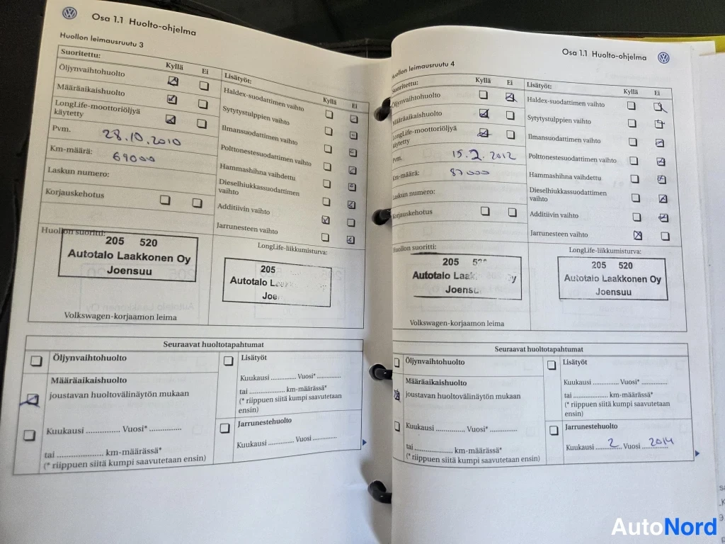 Muu: Auki avattu Volkswagenin huolto-ohjelman huoltoleimaruudut, joissa käsinkirjoitetut huoltopäivämäärät ja jälleenmyyjän leimat.