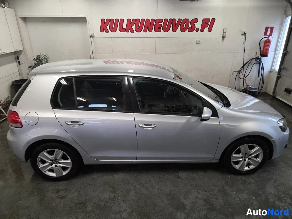 Takaviisto: Hopeanvärinen viisiovinen hatchback sivusta-takaapäin kuvattuna hallitilassa.