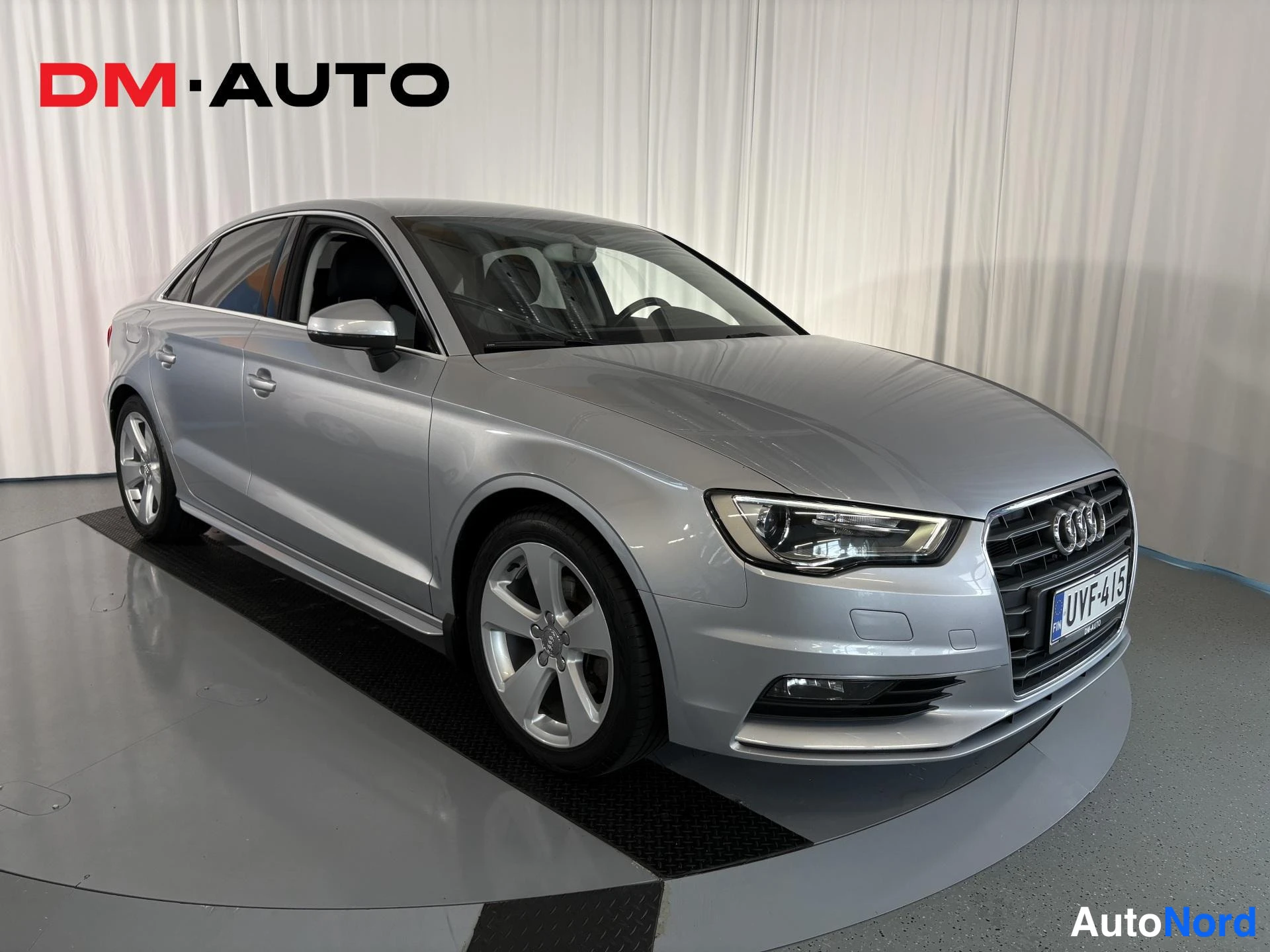 Etuviisto, nokka oikealle: Hopeanharmaa Audi A3 -sedanin etunurkka oikealta; etusäleikkö, ajovalot ja rekisterikilpi näkyvissä.