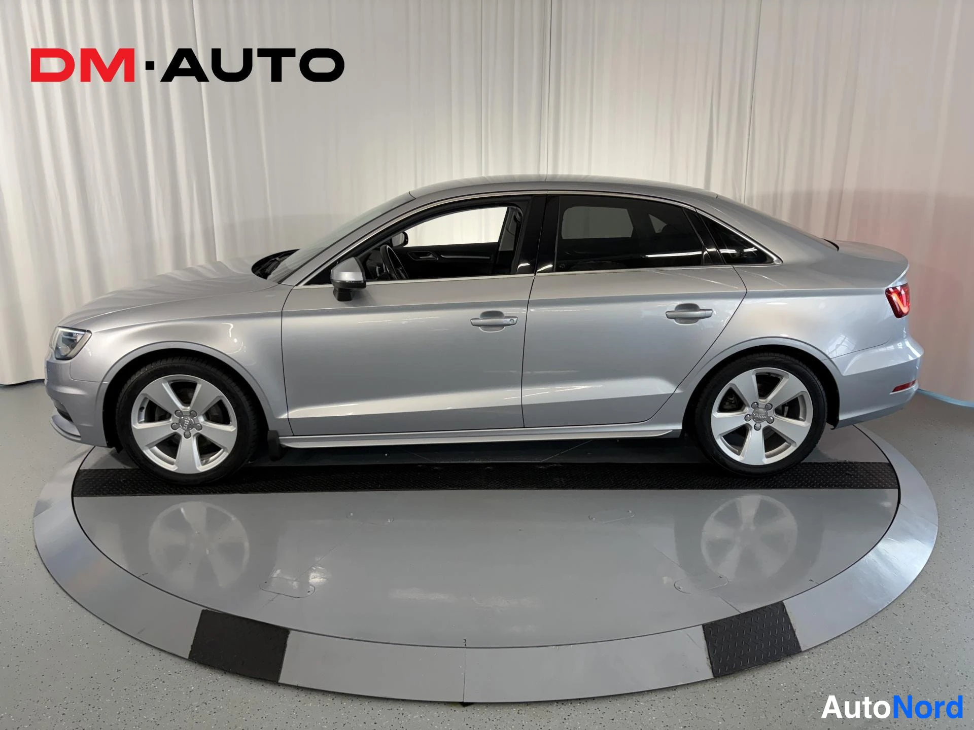 Sivulta: Audi A3 -sedanin sivunäkymä vasemmalta; hopeaa korirakennetta, viisi oviaukkoa, tummat ikkunat ja valkometallivanteet.