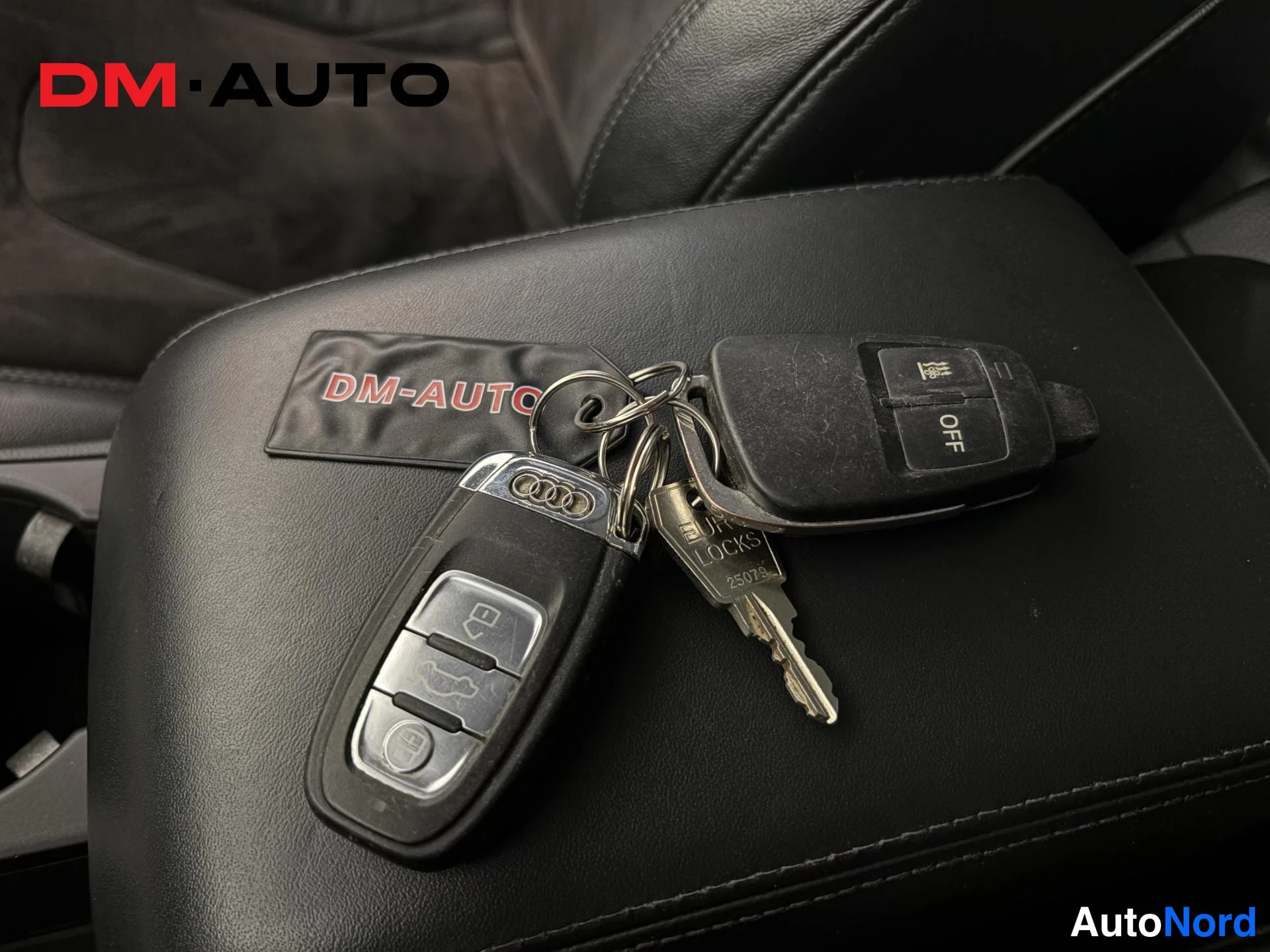 Muu: Musta nahkapäällysteinen keskihöylä jonka päällä kaksi Audi-avainpäätä ja metalliavain 'DR LOCKS 25075' tekstillä.