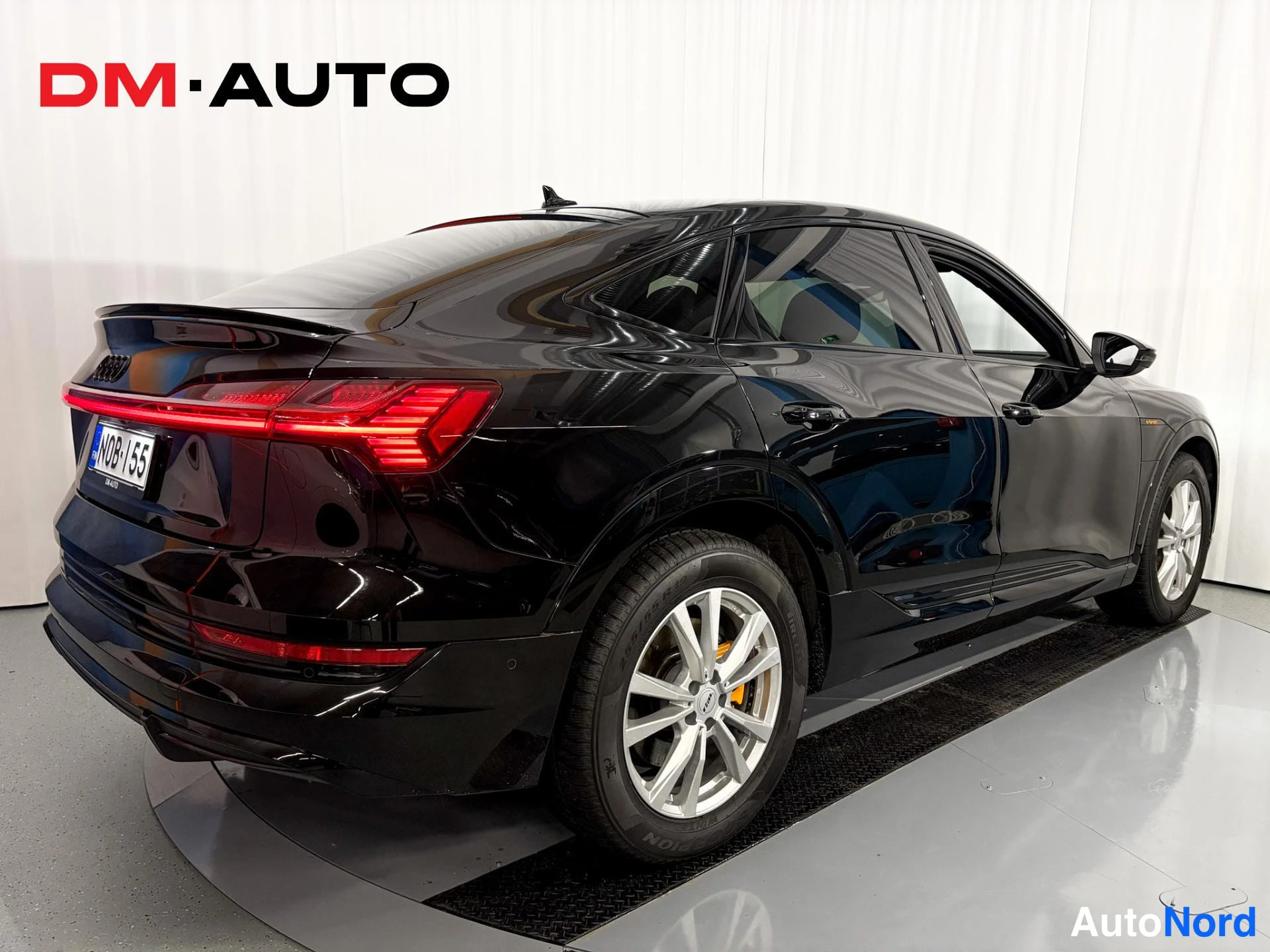 Takaviisto: Audi e-tron Sportback -musta takaviistokuva, näkyvissä punaiset takavalot, rekisterikilpi ja hopeiset vanteet.