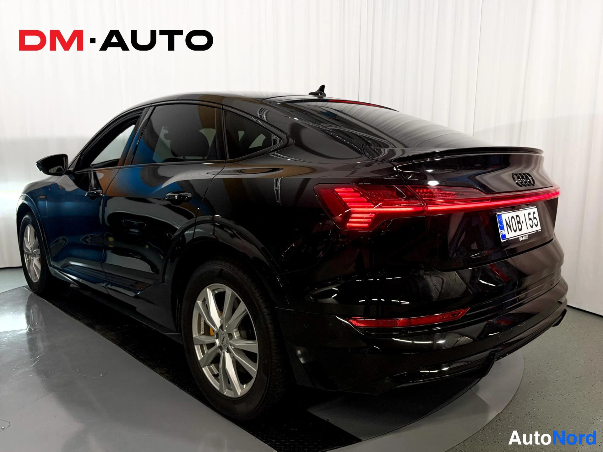Takaviisto: Audi e-tron Sportback mustana takaviistosta oikealta; punainen takavalokenraali, korkea spoileri ja hopeavatokset.
