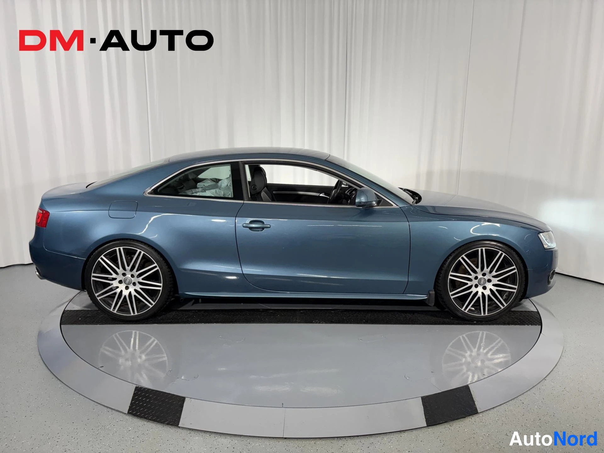 Sivulta: Sinisenharmaa Audi A5 -coupé kyljestä sivulta, kaksiovisen korin ja monihaaraiset kevytmetallivanteet näkyvissä.