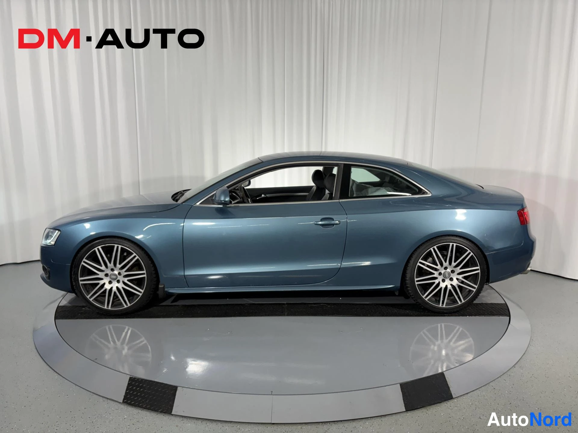 Sivulta: Sininen Audi A5 -coupe sivulta kuvattuna, näkyvissä profiili, kiinni ovet ja hopeamonet vanteet.
