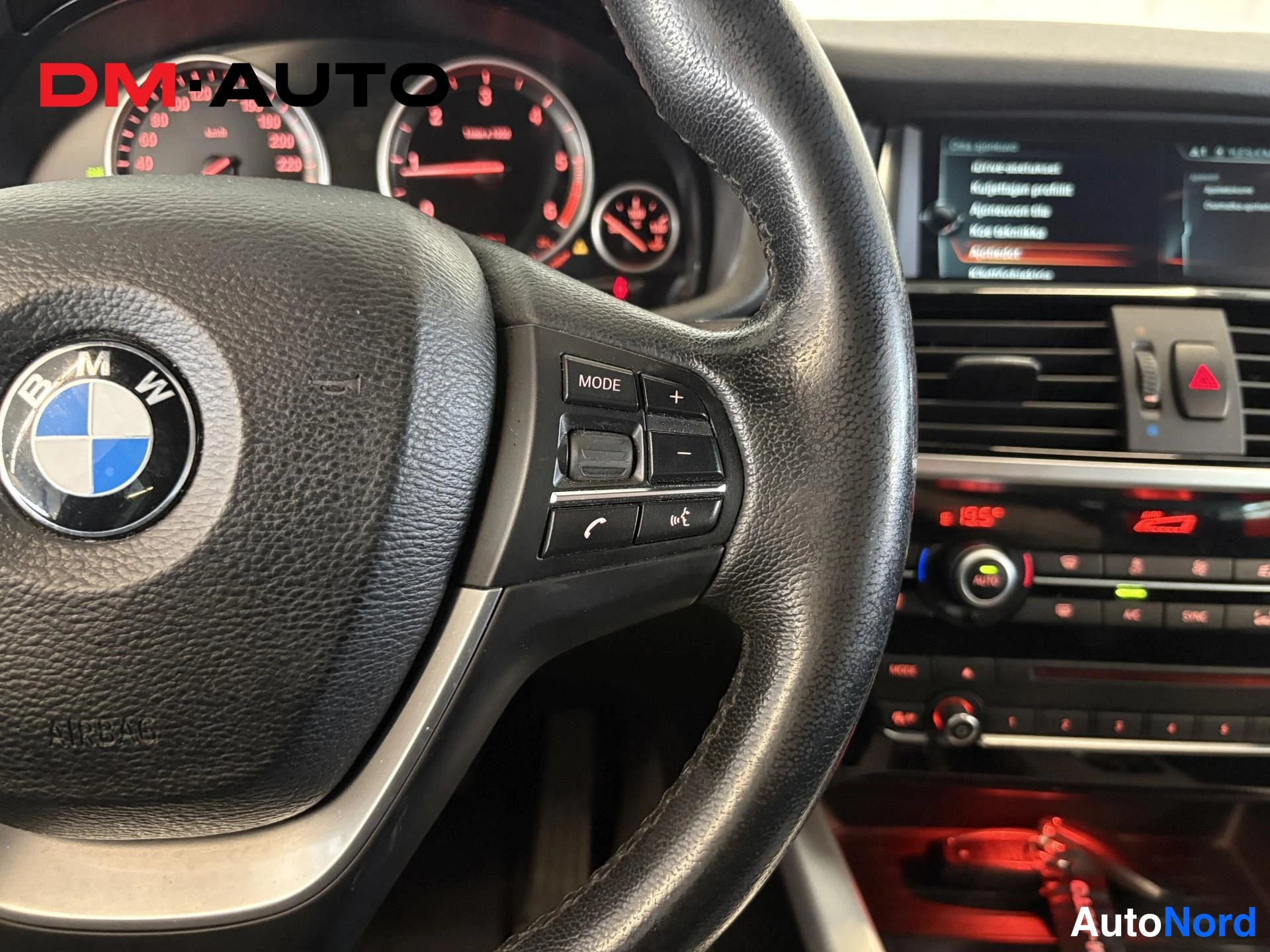 Yksityiskohta: BMW-ohjauspyörä MULTIMEDIA-MODE-, puhelin- ja ääniohjauskomponenteilla, taustalla mittaristo, infotainment-näyttö ja ilmastointipaneeli.