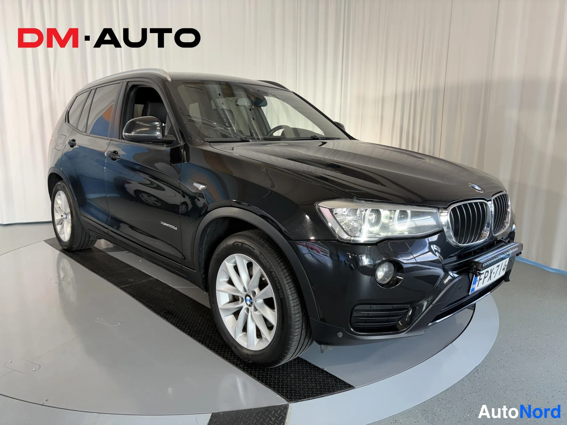 Etuviisto, nokka oikealle: Musta BMW X3 etuviistosta oikealta, kylki ja etupää näkyvät, valokuvausliikkeen studio-tausta.
