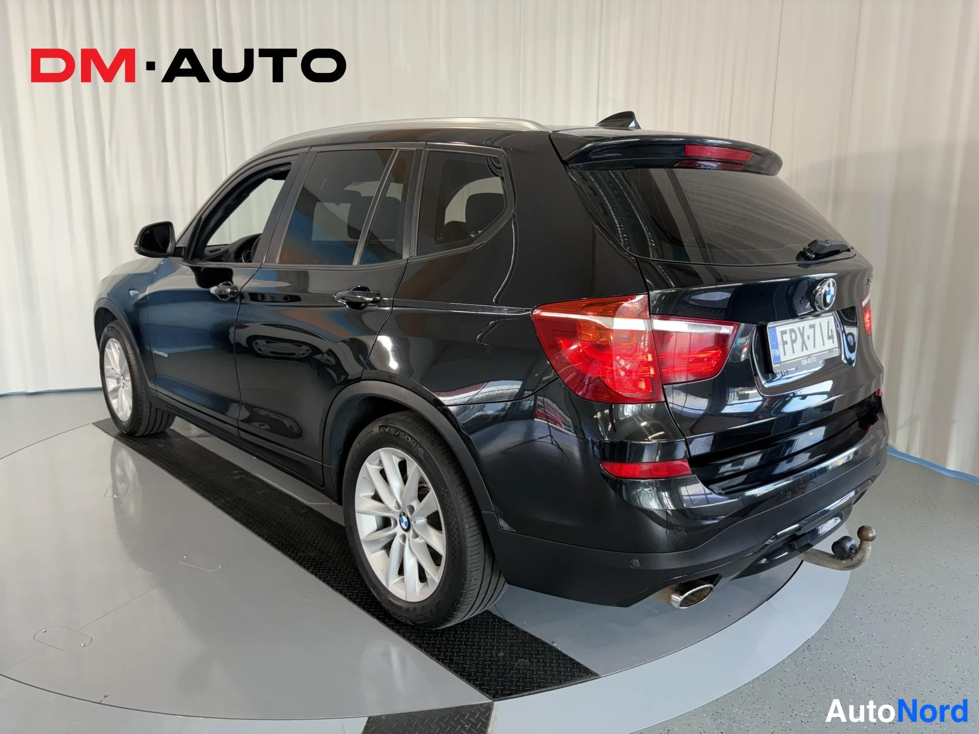 Takaviisto: Mustan BMW X3:n takakolmannes, rekisterikilpi, katkaisinetroit takana.