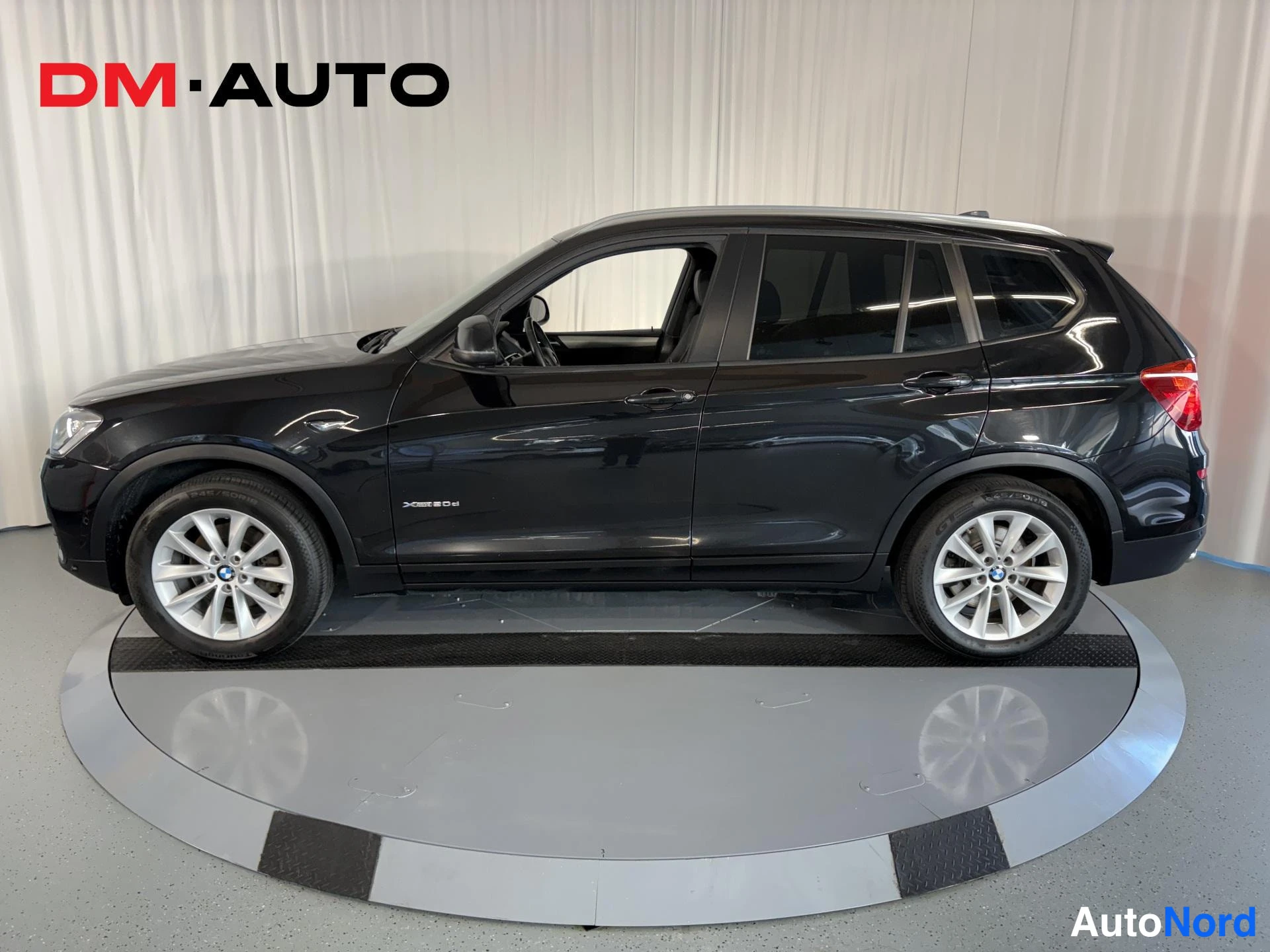 Sivulta: Mustan BMW X3:n sivukuva vasemmalta, neljä ovea ja hopeavanteet näkyvissä.