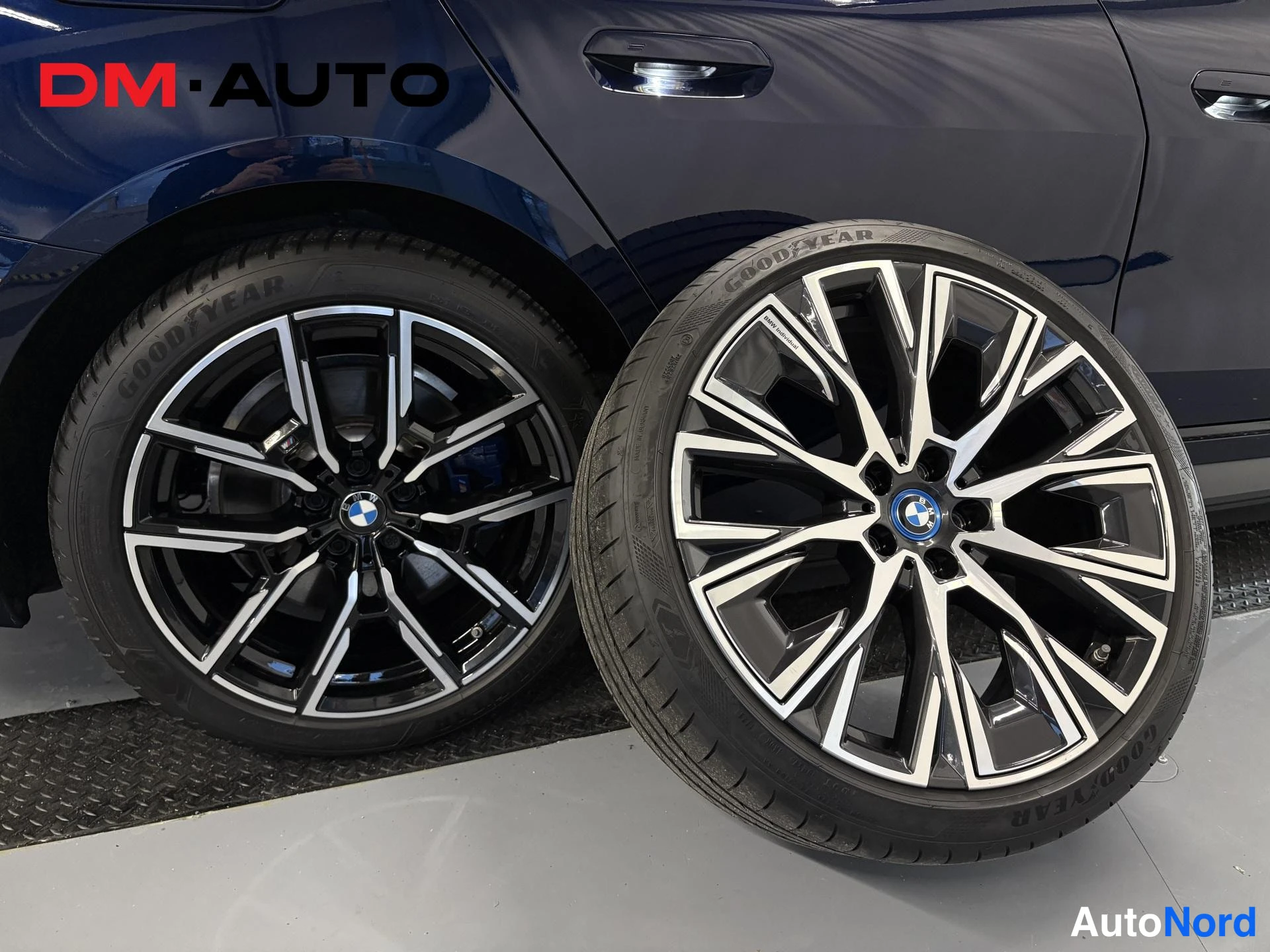 Sivulta: Kaksi Goodyear-renkailla varustettua BMW-vantea kuvattuna auton tummansinisen ovipaneelin edessä; toinen vanta­pär on asennettuna autossa.
