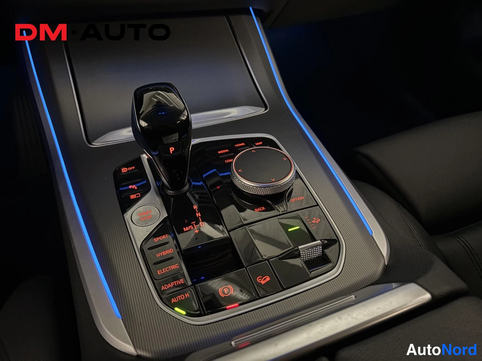 Muu: Keskiosta: vaihteenvalitsija asennossa P, iDrive-säädin ja napit SPORT, HYBRID, ELECTRIC, ADAPTIVE, AUTO H sekä käynnistyspainike.