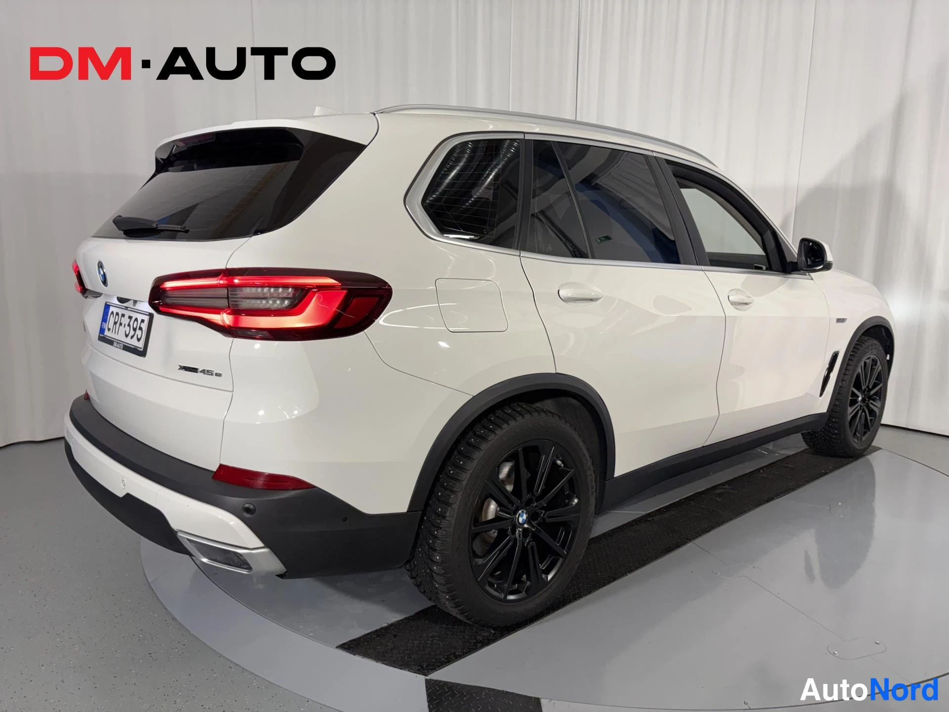 Takaviisto: Valkoisen BMW X5:n takaosa ja vasen sivu kulmasta kuvattuna; takavalot, -kilpi ja mustat vanteet näkyvissä.