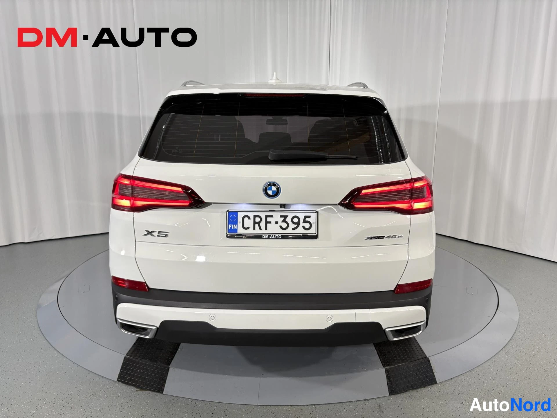 Takaa: Valkoisen BMW X5:n takaosa suoraan takaa; X5-merkintä, XDrive45e-teksti, -kilpi ja neljä pakoputkea näkyvissä.