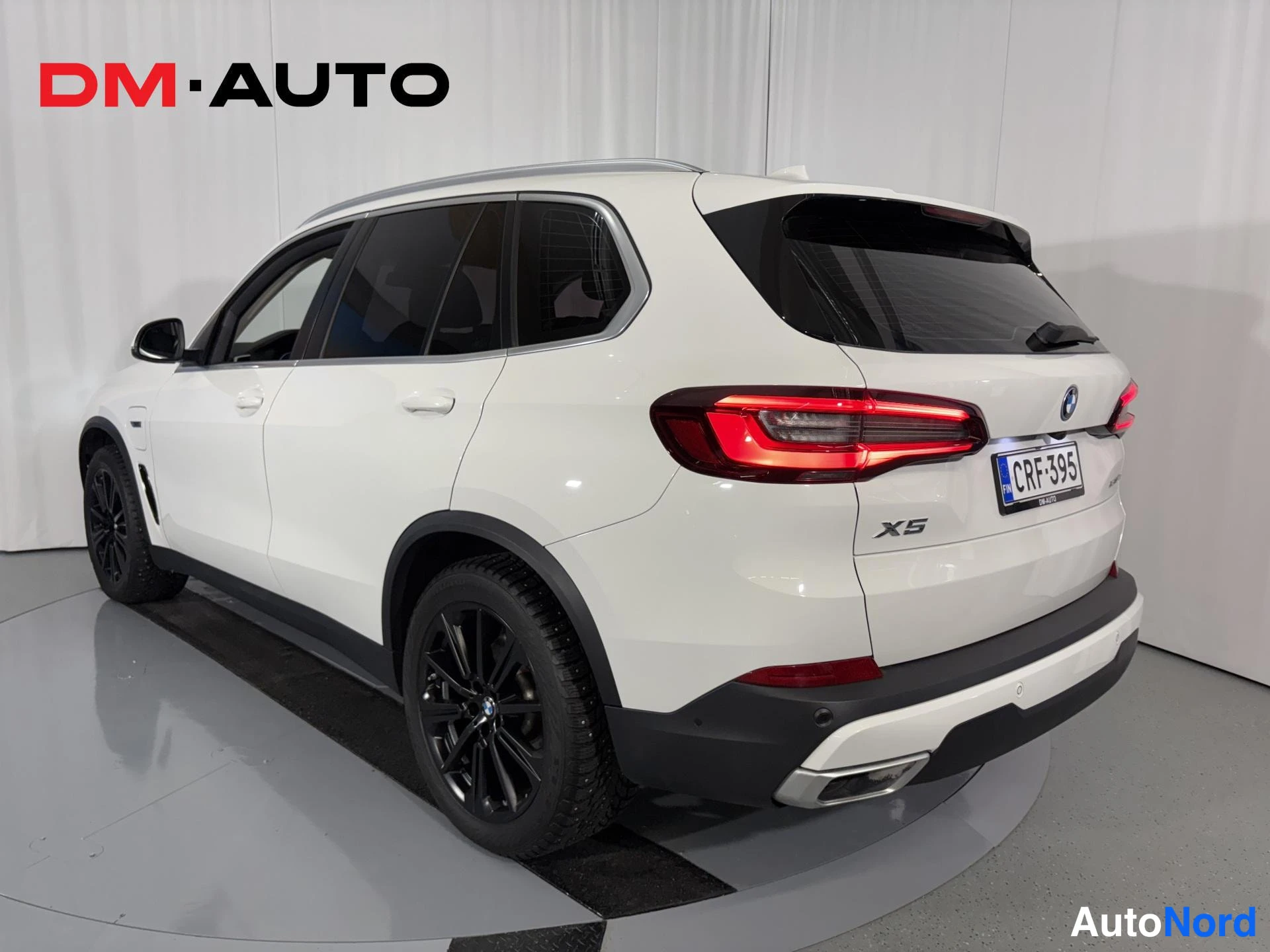 Takaviisto: Valkoisen BMW X5:n takaosa ja vasen sivu kulmasta kuvattuna; X5-merkintä, -kilpi ja mustat vanteet näkyvissä.