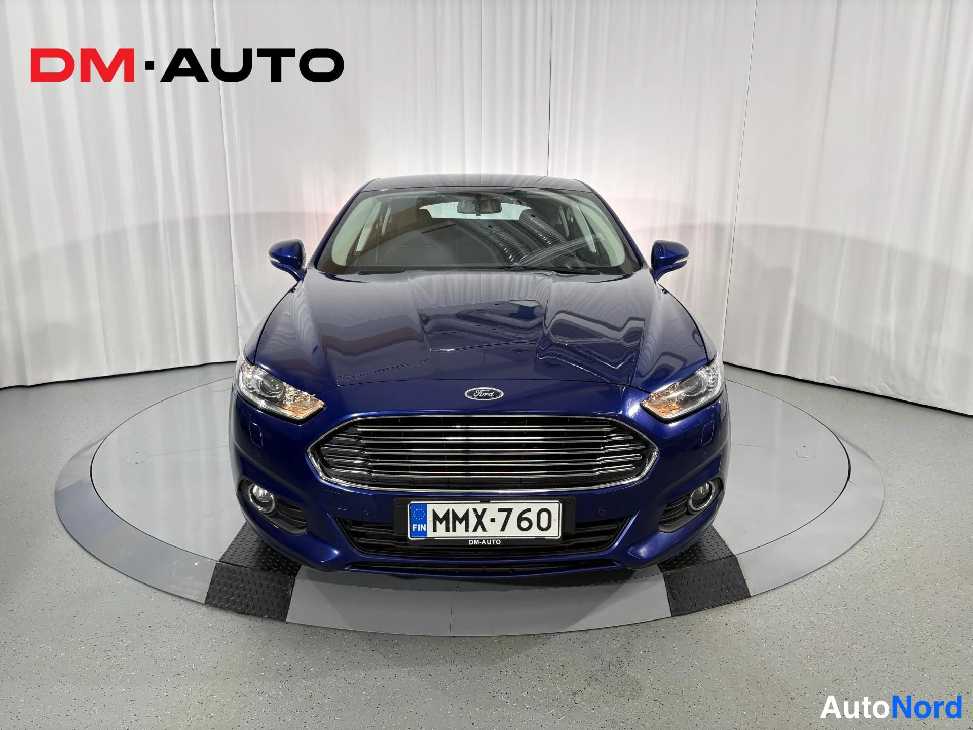 Edestä: Sininen Ford Mondeo suoraan edestä kuvattuna, rekisterikilpi.